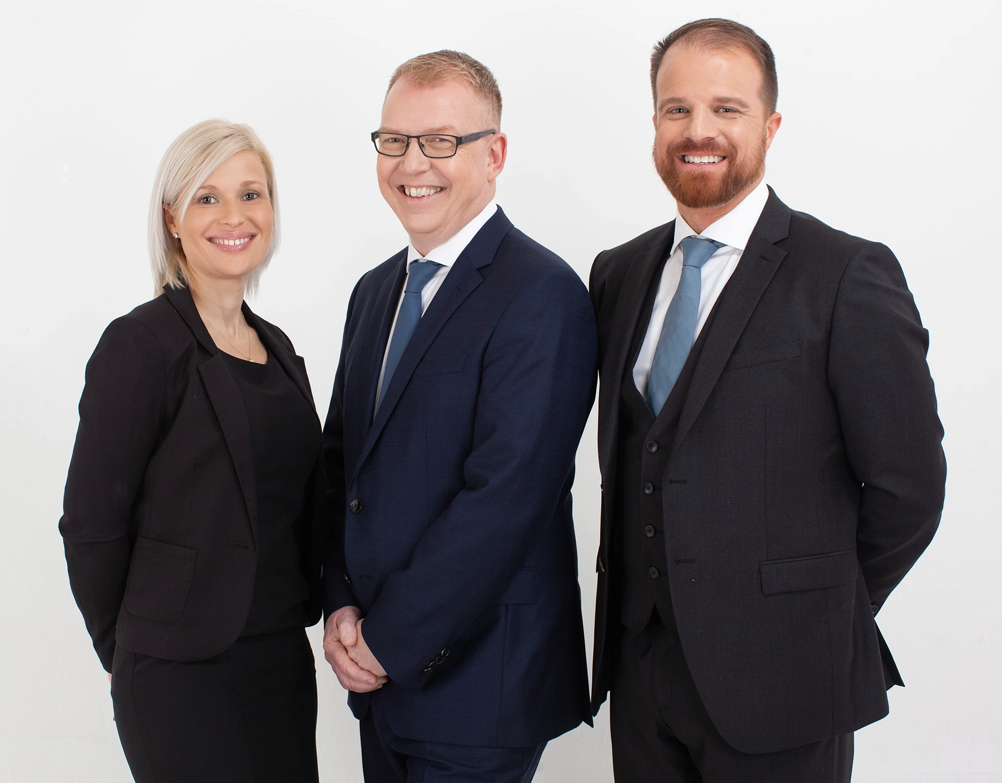 Three business professionals smiling in formal attire